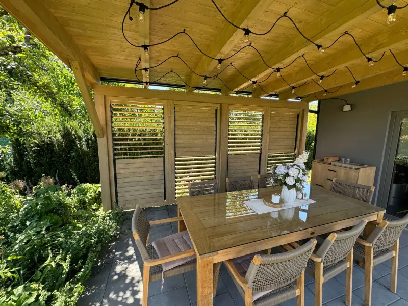 Drehlamellen aus Holz unter einer Pergola mit Sitzbereich